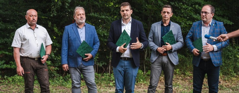 Ministři životního prostředí a zemědělství, hejtman Jihomoravského kraje, ředitel Lesů ČR a zástupce ředitele Agentury ochrany přírody a krajiny ČR stojí v řadě a v ruce drží desky s podepsaným memorandem.